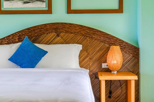 a bed with a wooden headboard and a table with a lamp at Southern Sun Homestay North in Kenting