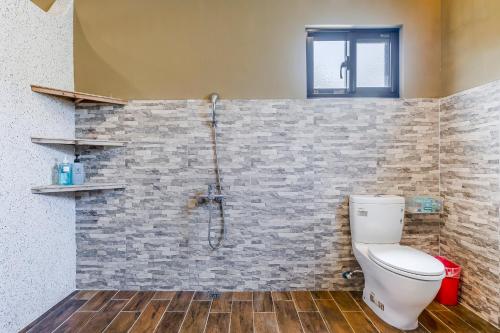 a bathroom with a toilet and a brick wall at Southern Sun Homestay North in Kenting