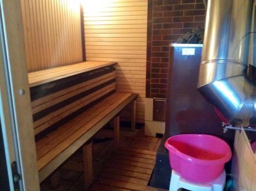 a small bathroom with a bench and a pink bucket at Aglonas Līdakas in Priežmale