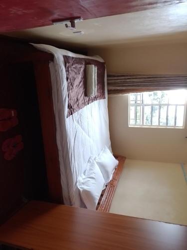 uma cama num pequeno quarto com uma janela em Eagles Haven Apartments Githunguri em Kamondo