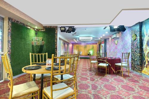 un comedor con paredes verdes, mesas y sillas en Hotel Red York By Byob Hotels en Noida