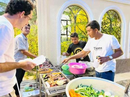 a group of men standing around a buffet of food at Hang Meas Boutique in Kampot