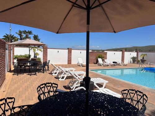 eine Terrasse mit einem Tisch, Stühlen und einem Pool in der Unterkunft Bajamar-Campo de Golf frente al mar in Ensenada