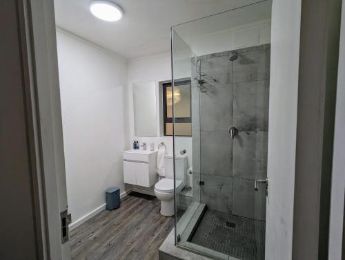 a bathroom with a toilet and a glass shower at Modern Retreat in District Six in Cape Town
