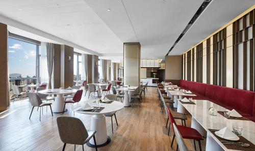 a restaurant with white tables and chairs and windows at Holiday Inn Shanghai Huaxia, an IHG Hotel - overlooking city scenery at Sky View Restaurant in Shanghai