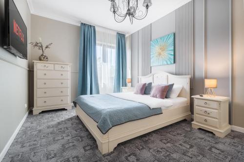 a bedroom with a bed with blue curtains and a chandelier at Moonlight Central Apartments in Oradea