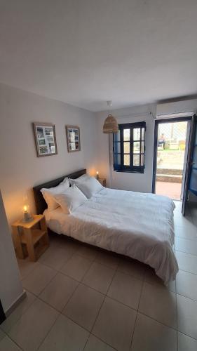a bedroom with a large white bed and a window at Oros Eros 2 in Hydra