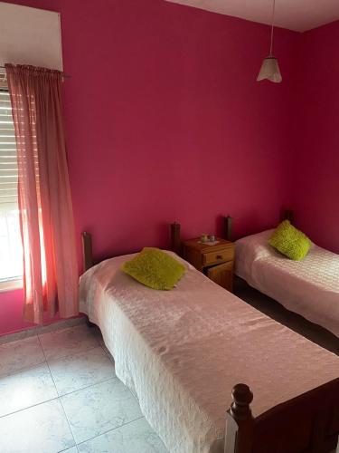 1 Schlafzimmer mit 2 Betten und einer lila Wand in der Unterkunft Conti House in Capilla del Monte