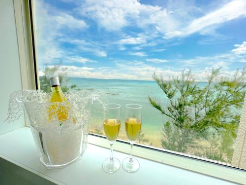 two glasses of wine sitting on a window sill at グランディオーソオーシャンビューヴィラ金武1 in Okinawa City