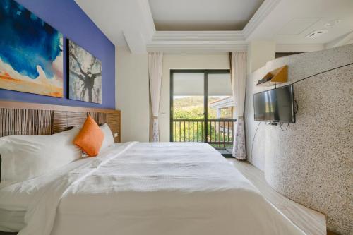 a bedroom with a bed with a tv on the wall at Southern Sun Homestay North in Kenting