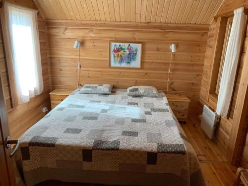 ein Schlafzimmer mit einem Bett in einer Holzhütte in der Unterkunft Mökki Aapola in Puumala
