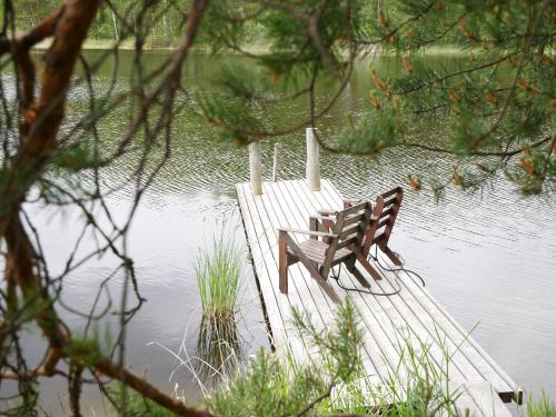 a wooden bench sitting on a dock in the water at Mökki Aapola in Puumala