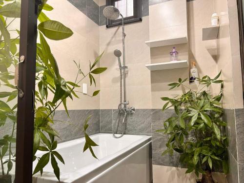a bathroom with plants and a shower with a tub at MUN HOMESTAY in Hue