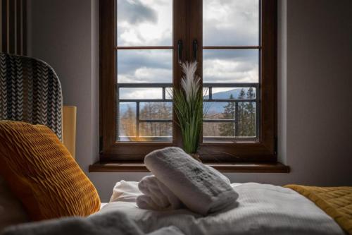 a bedroom with a window with a towel on a bed at Apartament C2 Green Resort z Basenem, Sauną, Jacuzzi - 5D Apartments in Szklarska Poręba