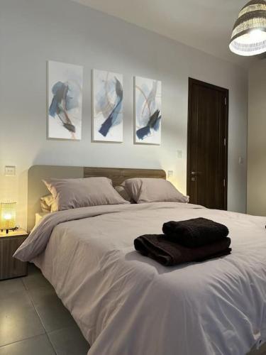 ein Schlafzimmer mit einem großen weißen Bett mit drei Bildern an der Wand in der Unterkunft Bluemoon Apartment in Marsaxlokk