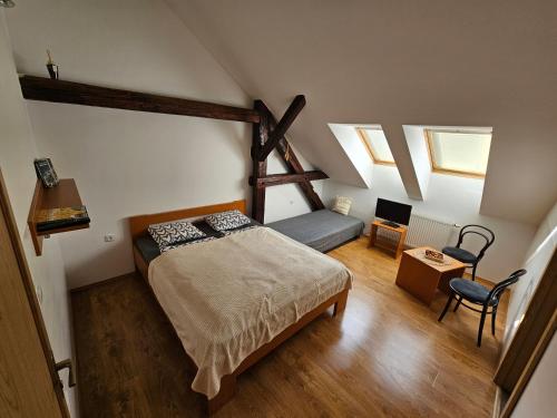 a attic bedroom with a bed and a chair at Penzion Podzámčí in Jaroslavice