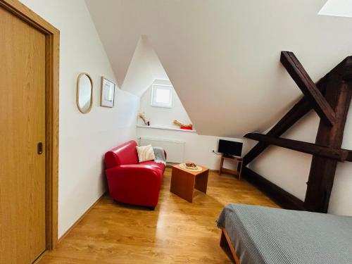 a attic room with a red chair and a bed at Penzion Podzámčí in Jaroslavice