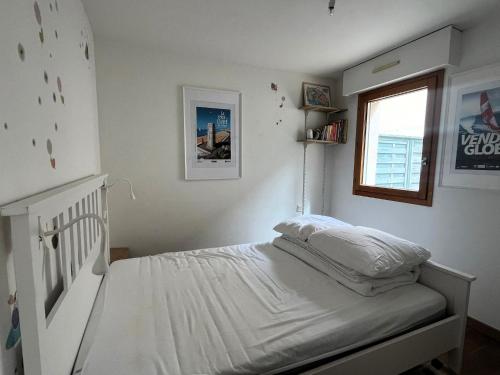 um quarto com uma cama com lençóis brancos e uma janela em La Terrasse em Les Sables-dʼOlonne