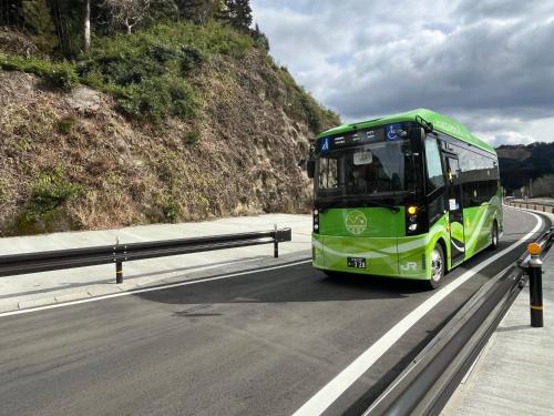 a green bus is driving down a highway at ほうしゅ楽舎 in Asakura