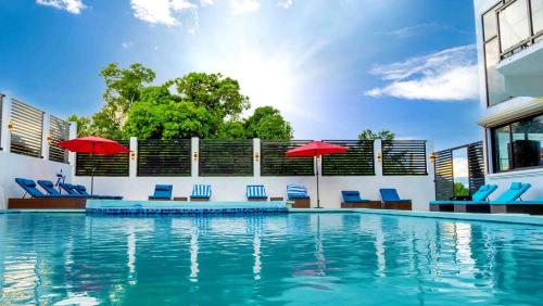 a swimming pool with blue chairs and red umbrellas at The Alexandria Marquis Hotel and Resort in San Ignacio