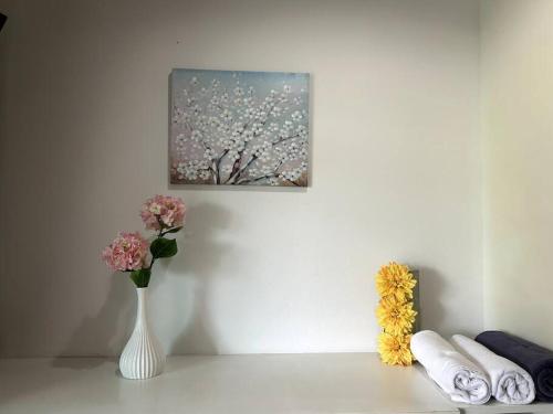 a white table with a vase of flowers and a painting at Condo Joe in Central Hua Hin in Hua Hin
