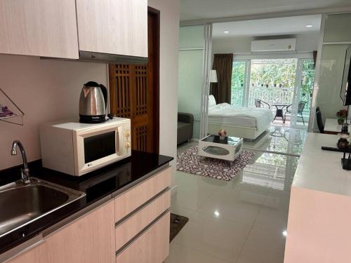 a kitchen with a microwave and a room with a bed at Baan Klang Condo in Central Hua Hin in Hua Hin