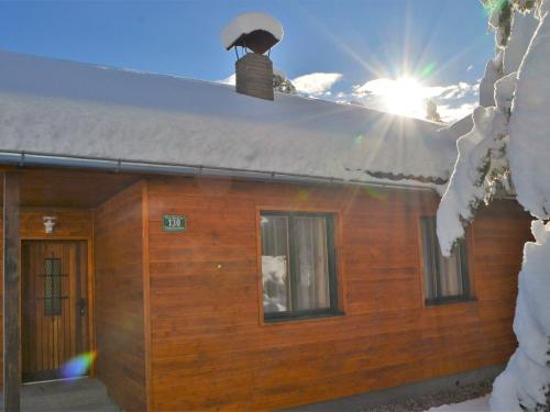 a log cabin with snow on the roof and the sun at Sunlit Cabin with Jacuzzi in Turracherhohe in Turracher Hohe