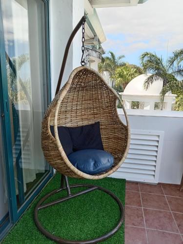 a hanging rattan chair with a blue pillow on a balcony at De Leon Staycation at Vista de Loro in Ternate