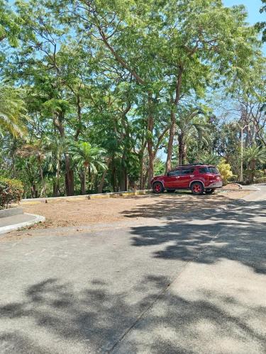 a red car parked in a parking lot with trees at De Leon Staycation at Vista de Loro in Ternate