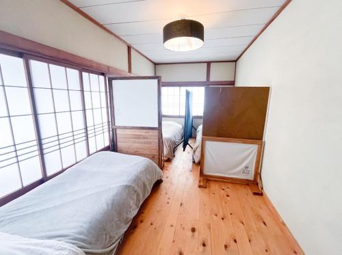 ein Schlafzimmer mit einem Bett in einem Zimmer mit Fenstern in der Unterkunft Dormitory SLOW HOUSE Kesennuma- Vacation STAY 30914v in Kesennuma