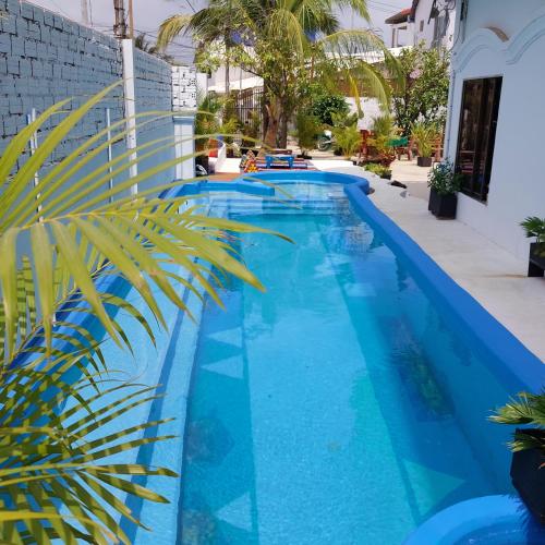 una piscina azul con una palmera al lado en Villa Tropica en Kampot
