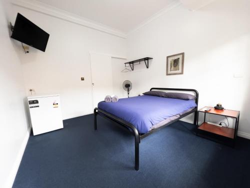 1 dormitorio con 1 cama y TV. en Somewhere To Stay Backpackers, en Brisbane