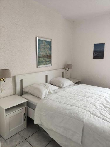ein Schlafzimmer mit einem großen weißen Bett und einem Nachttisch in der Unterkunft Résidence Palmyra - 2 Pièces pour 4 Personnes 764 in Le Barcarès