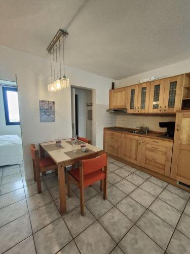 eine Küche mit einem Tisch und Stühlen sowie eine Küche mit Schränken in der Unterkunft Résidence Palmyra - 2 Pièces pour 4 Personnes 764 in Le Barcarès