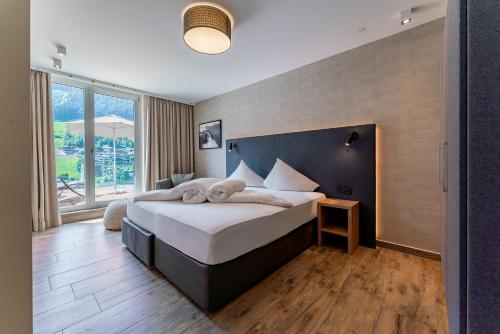 a bedroom with a large bed and a large window at Adler Resort in Saalbach-Hinterglemm