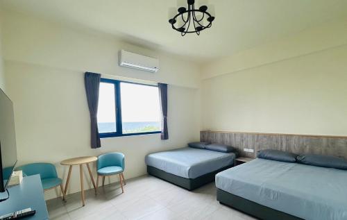 a bedroom with two beds and a tv and a window at 綠島209角落Corner of Green Island 台東縣民宿編號第2003號 in Green Island
