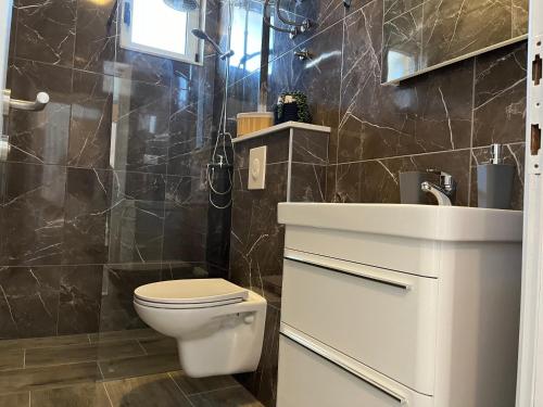 y baño con aseo, lavabo y ducha. en Apartment Makarska M&I, en Makarska