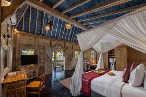 um quarto com uma cama e uma televisão num quarto em Wooden Ganeca Villas by Pramana Villas em Ubud