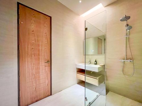 a bathroom with a shower and a sink and a glass door at Baan Tah On The Sea in Bang Sare
