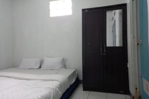 a bedroom with a bed and a black door at OYO 93847 Blio Guest House Syariah in Bandung