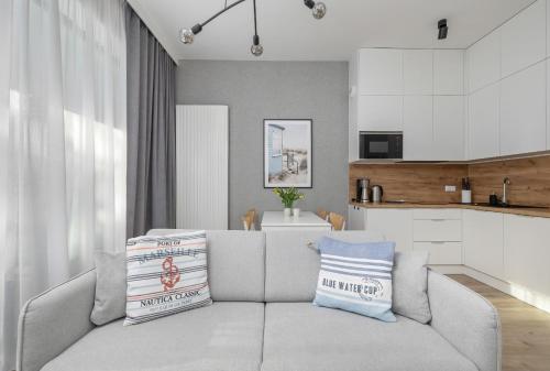 a living room with a couch and a kitchen at Apartament Relax z Balkonem Shellter Rogowo Renters Prestige in Rogowo