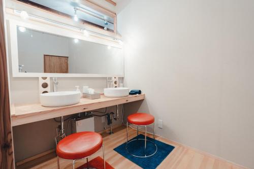 Dormitory SLOW HOUSE Kesennuma- Vacation STAY 30914v في Kesennuma: حمام به مغسلتين ومقعدين حمراء