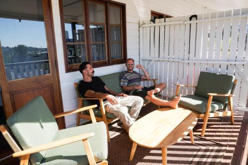 two men sitting on a porch with chairs at Somewhere To Stay Backpackers in Brisbane