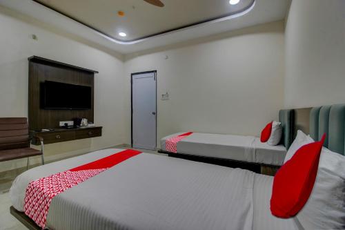 a bedroom with two beds with red pillows and a tv at BHILVA INN in Warangal