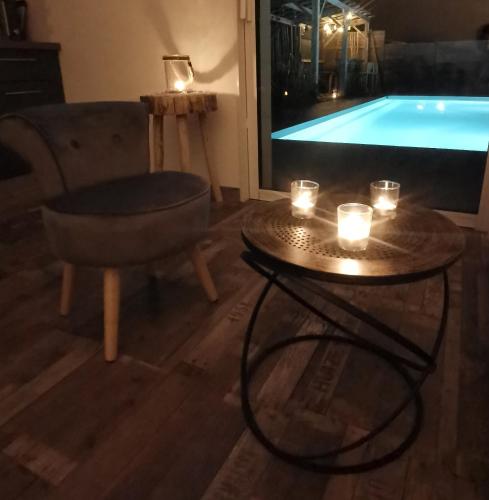 - un salon avec une télévision et une table avec des bougies dans l'établissement Logement cosy avec piscine et jacuzzi privatifs 4 étoiles, à Saint-Dolay