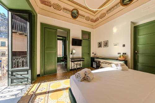 a bedroom with two beds with green doors and a desk at Palazzo Villelmi in Cefalù