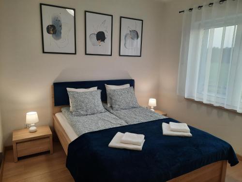 a bedroom with a blue bed with two towels on it at Chabrowa Apartamenty 2 in Milicz