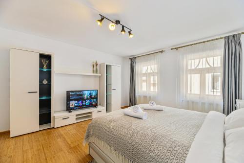 a white bedroom with a bed and a tv at Ceahlau Cozy House in Braşov