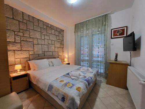 sypialnia z dużym łóżkiem i kamienną ścianą w obiekcie Apartments Mitrovići Miločer w miejscowości Sveti Stefan