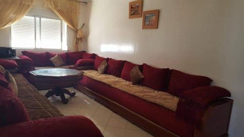 a living room with a red couch and a table at Appartement bien meublé à martil in Martil